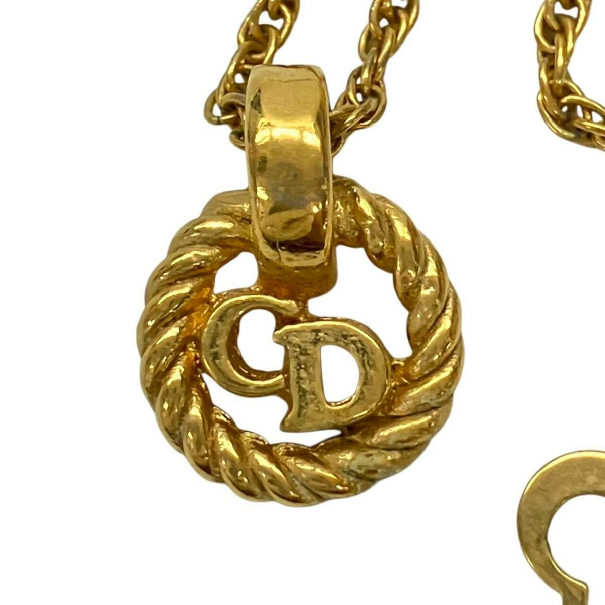 Close-up of the gold-colored CD logo twisted-rope pendant with part of its chain visible.
