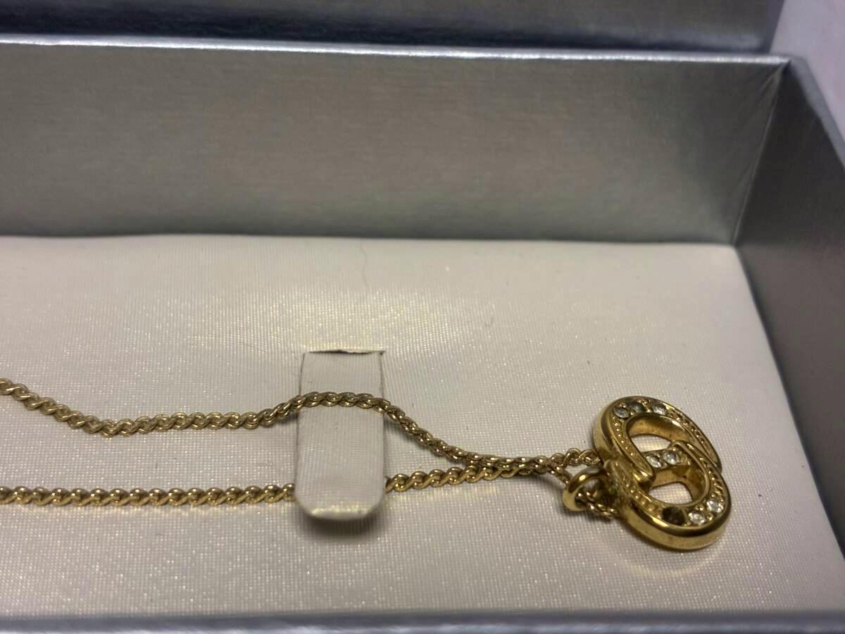 Gold-tone Christian Dior necklace with a CD pendant set with clear stones, shown in a jewelry box.