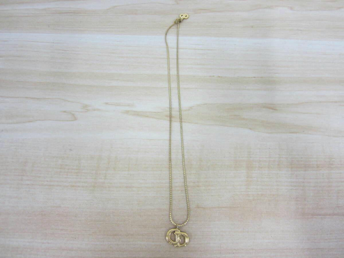 Gold-tone Christian Dior necklace with interlocking CD pendant laid flat on a light wood surface.
