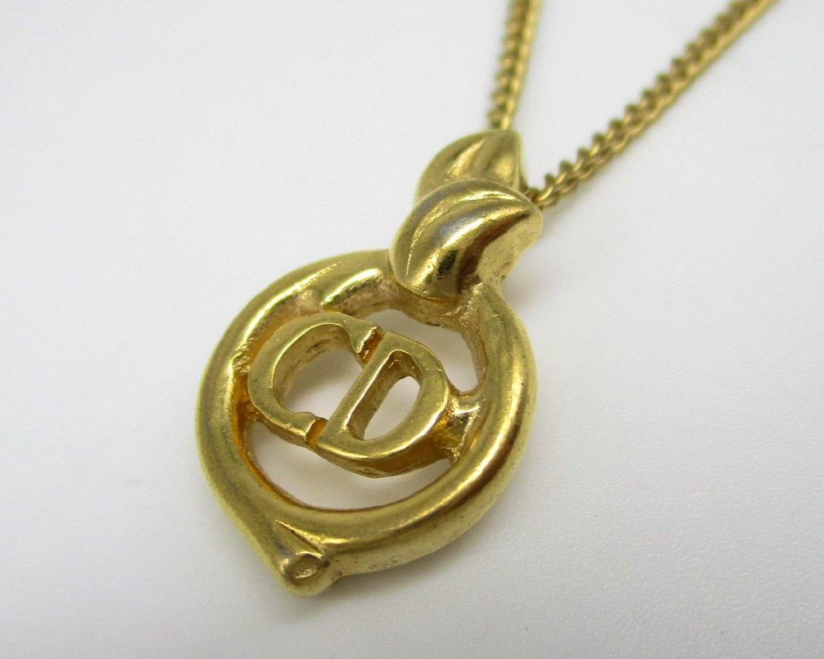 Close-up of the Christian Dior "CD" pendant on a gold-tone necklace chain.