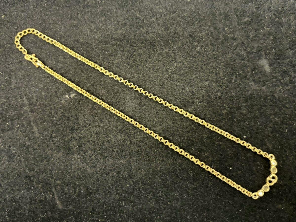 Gold-colored Christian Dior rhinestone necklace laid flat on a black surface, showing the chain and small rhinestone detail.