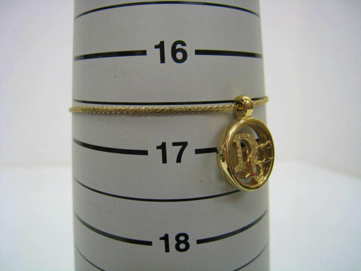 Gold-colored Christian Dior logo bracelet with a round circle-logo charm displayed on a sizing cone marked 16–18.