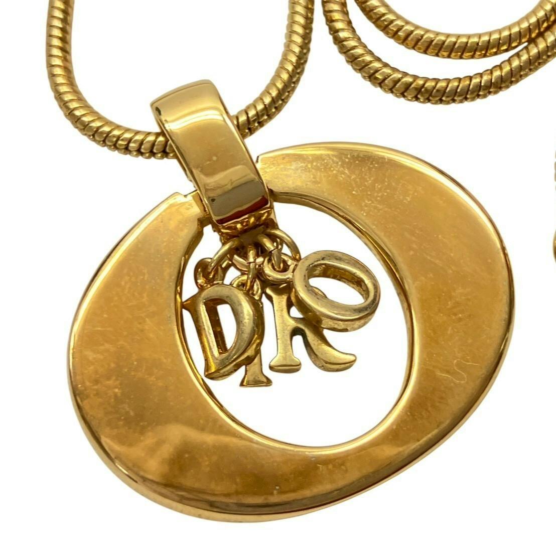 Close-up of the Christian Dior circular pendant showing DIOR letter charms and the attached chain.