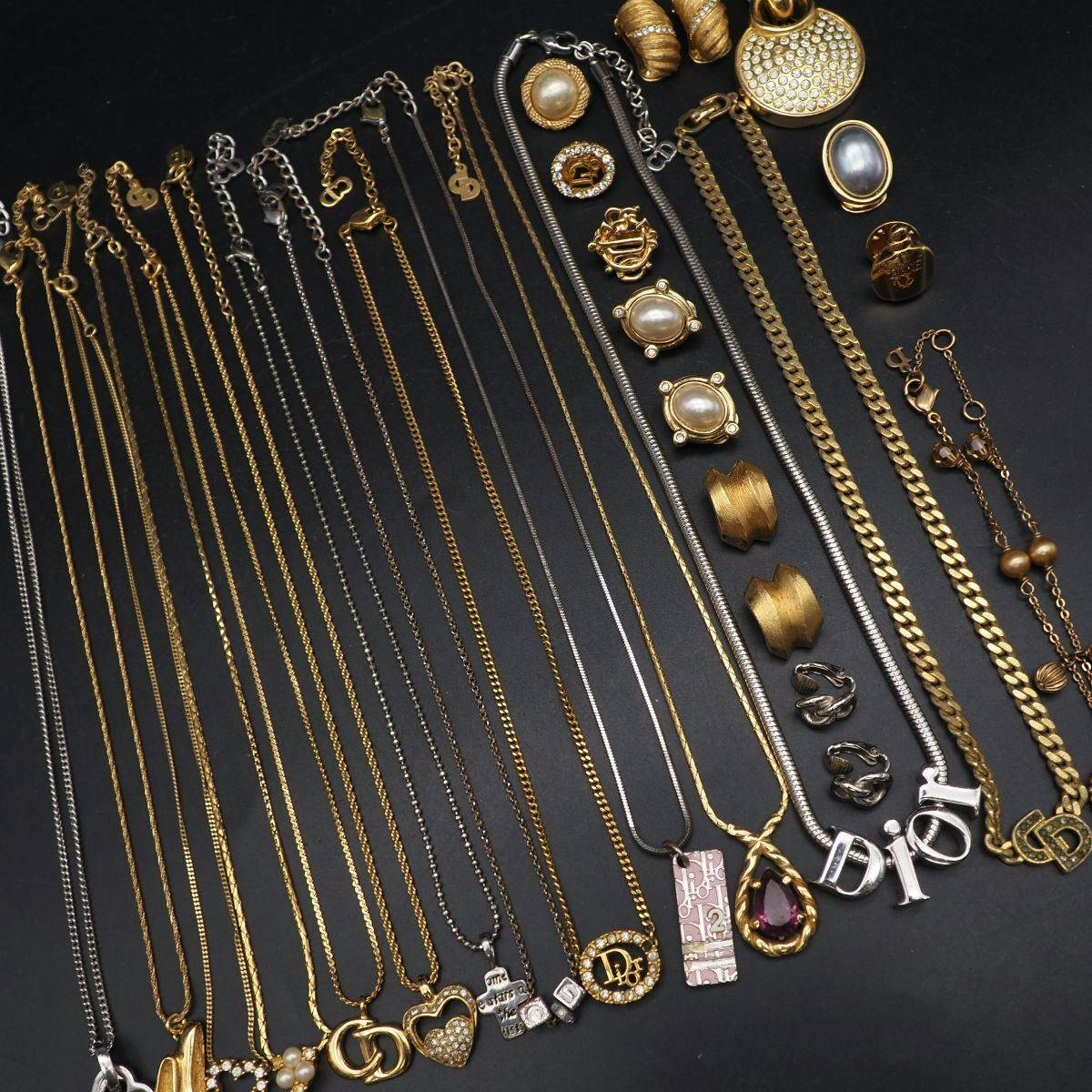 Multiple Christian Dior necklaces and other matching accessories laid out flat on a black background.