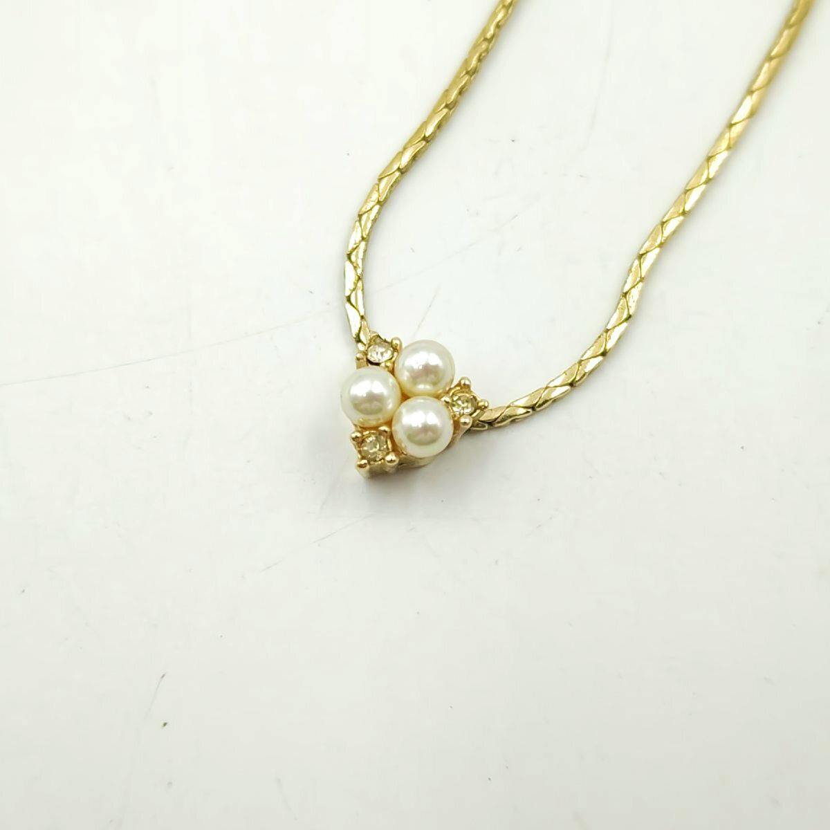 Close-up of the gold-tone Christian Dior necklace showing a cluster of three faux pearls with small rhinestones on a textured gold chain.