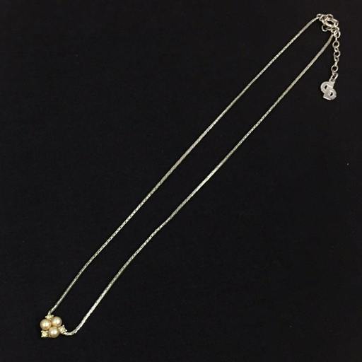 Silver-color Christian Dior necklace with a small cluster of three faux pearls on a thin chain displayed on a black background.