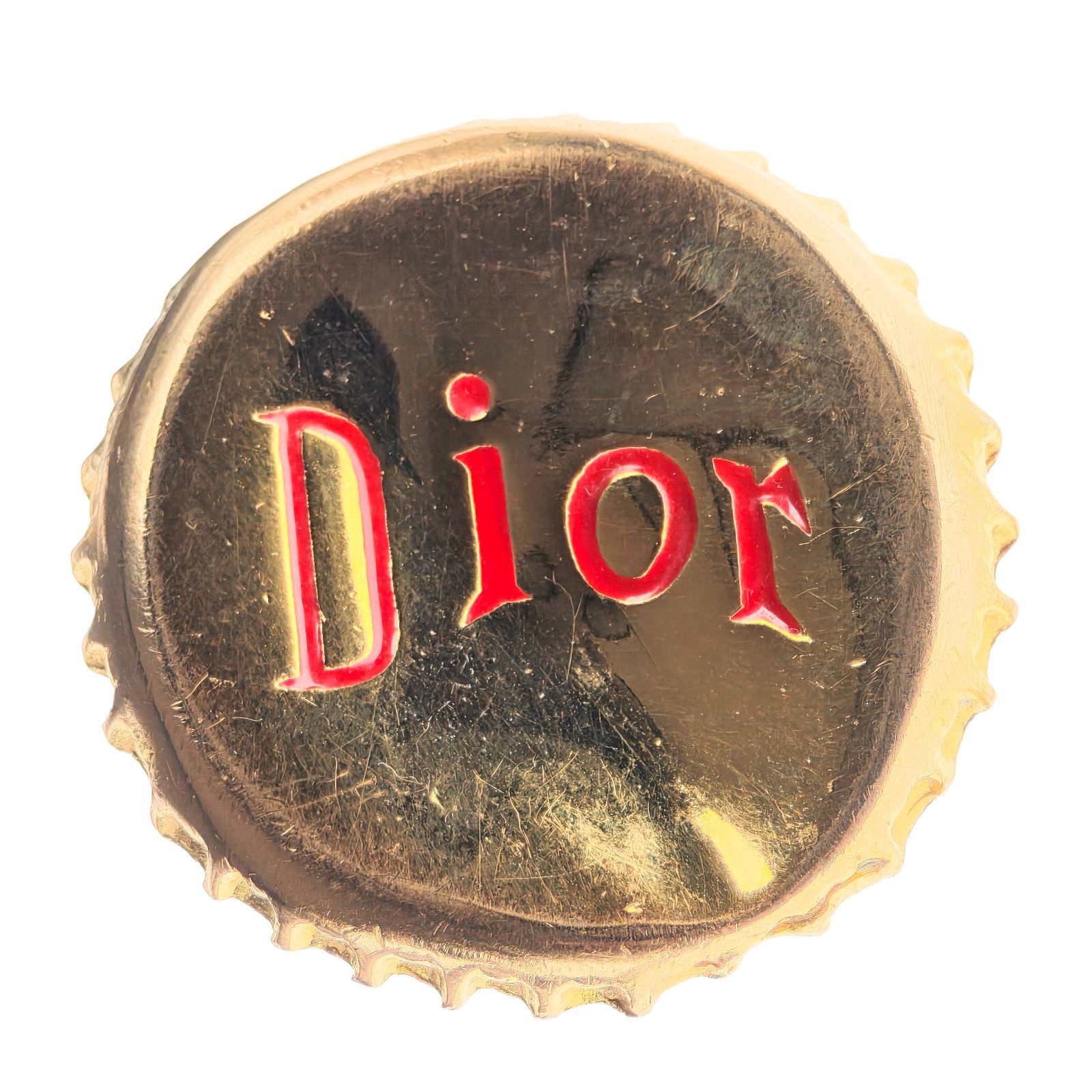 Close-up of a gold-tone bottle-cap motif ring face showing a red "Dior" logo.