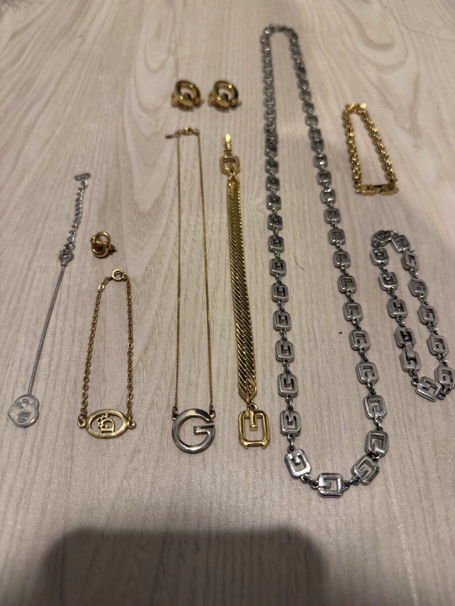 Assorted Dior and Givenchy necklaces, bracelets, and earrings laid out on a light wood surface.