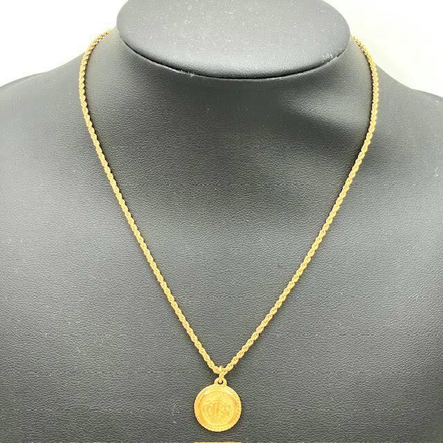 Gold-tone Christian Dior coin pendant necklace displayed on a black jewelry bust.