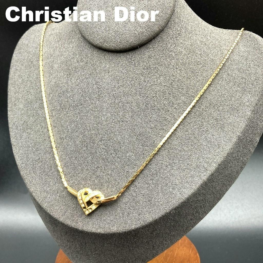 Gold-tone Christian Dior heart necklace with rhinestones displayed on a gray jewelry bust.