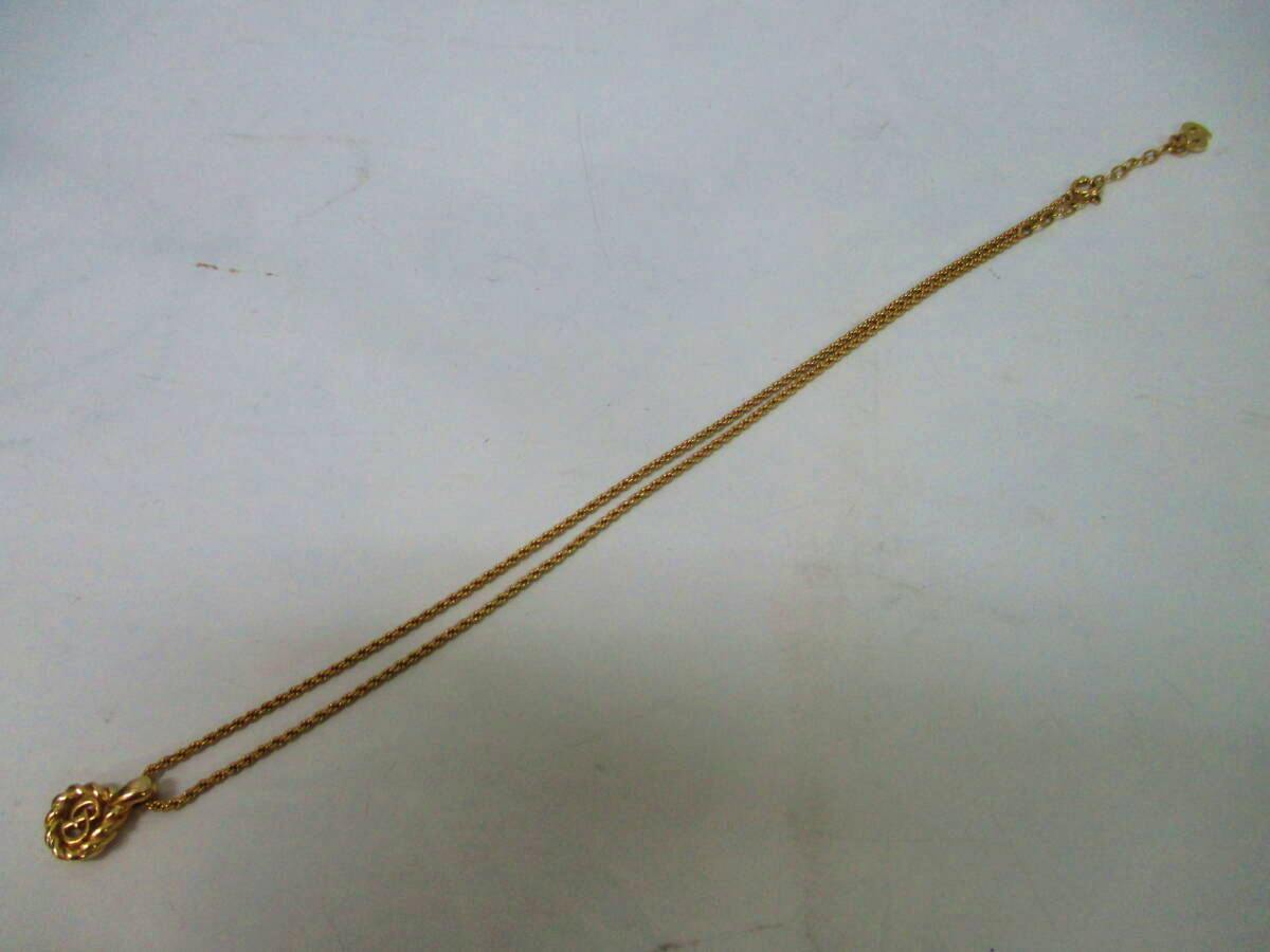 Gold-colored Christian Dior necklace with a small pendant laid flat on a white background.