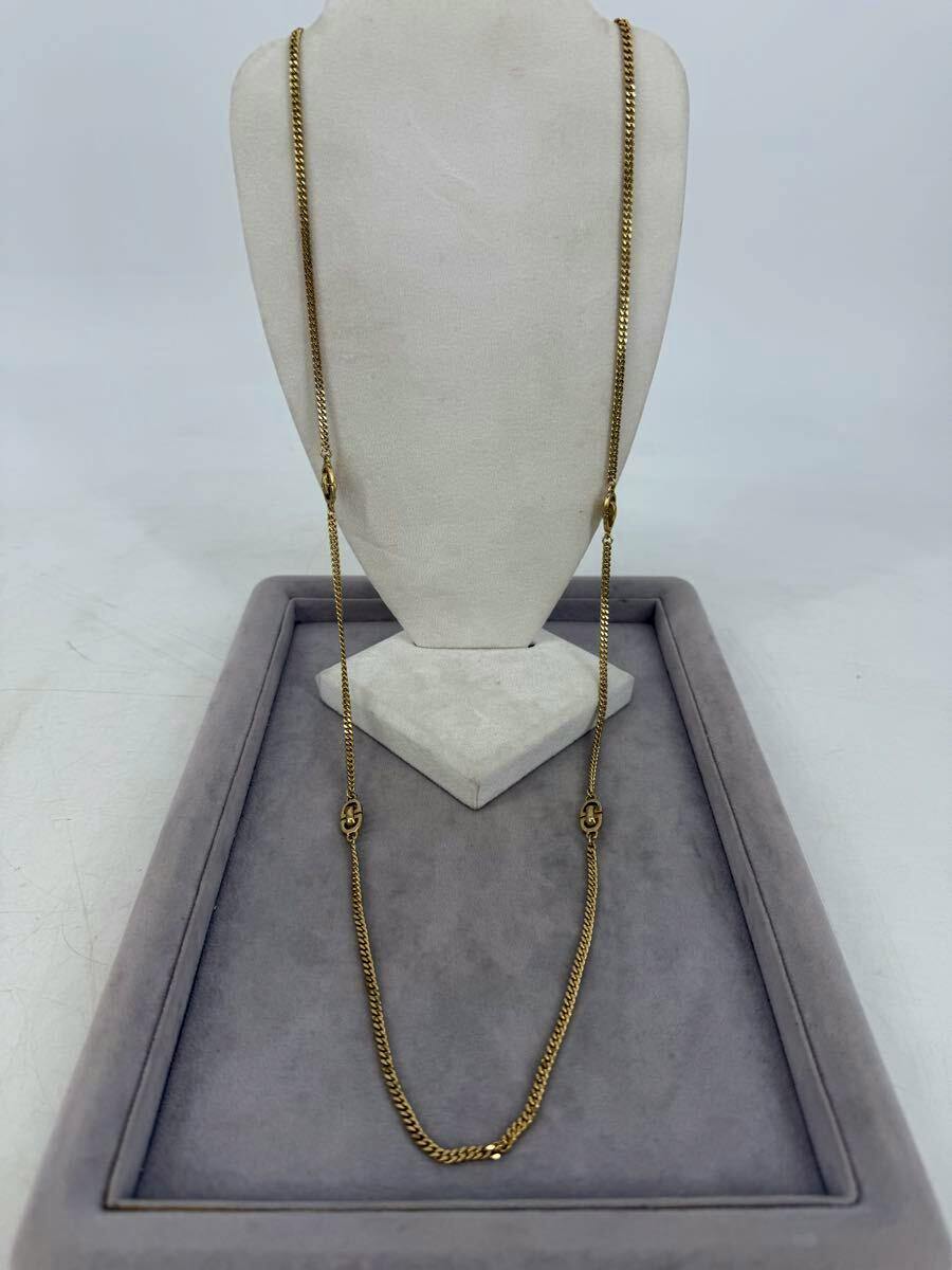Gold-tone necklace displayed on a white fabric jewelry bust over a gray display tray.