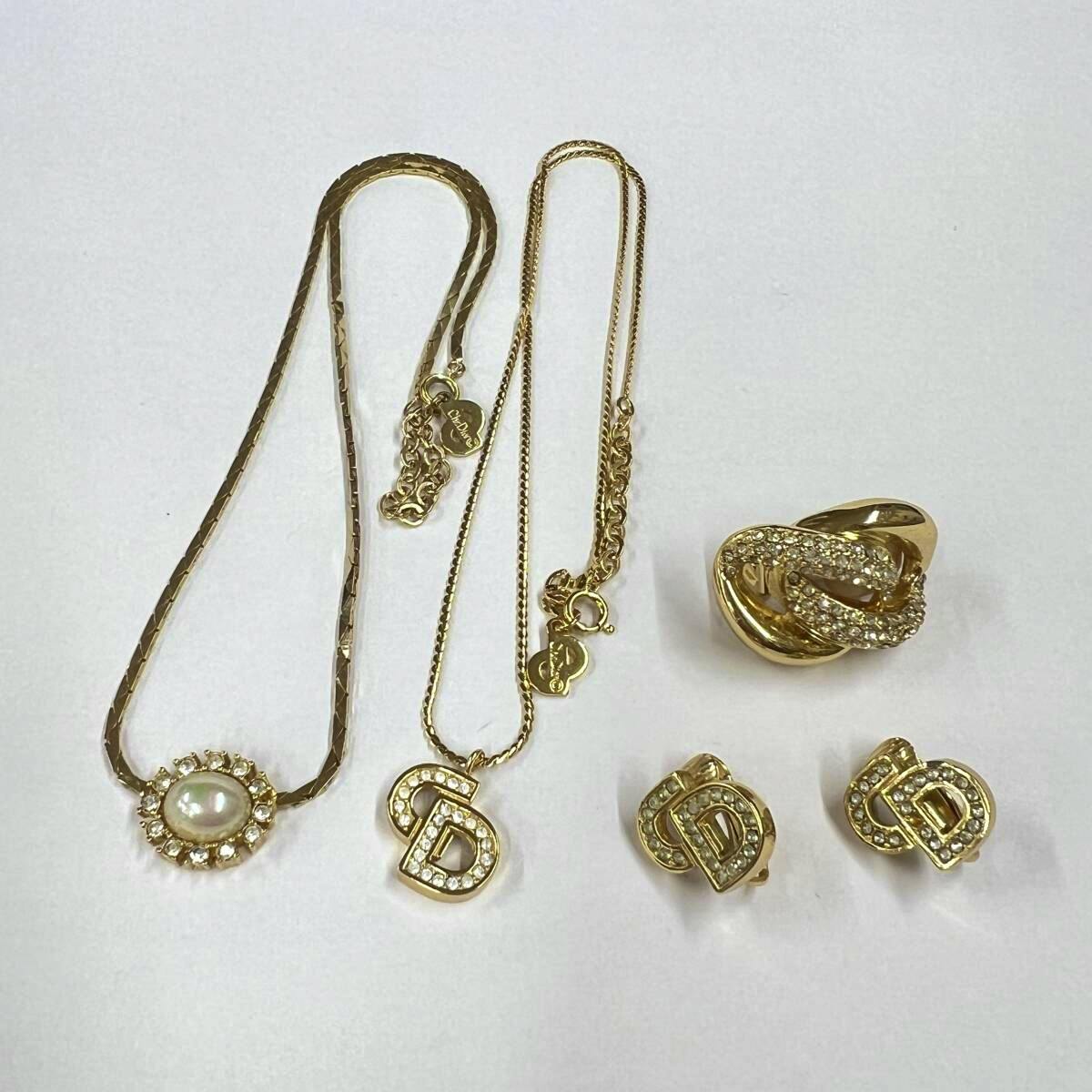 Two gold-colored Christian Dior necklaces and matching gold-colored earrings arranged on a white background.