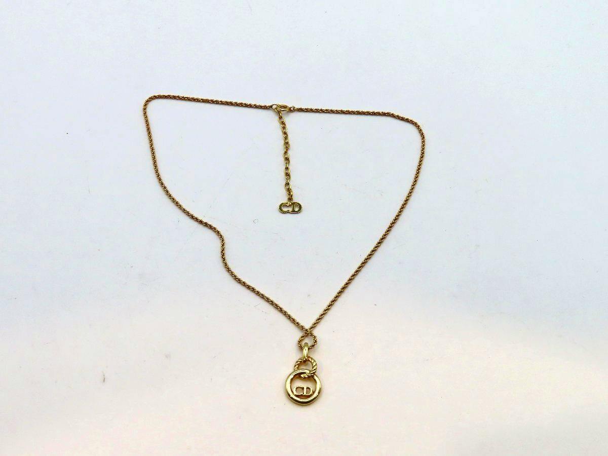 A plated Christian Dior necklace with a circular "CD" pendant displayed on a white background.