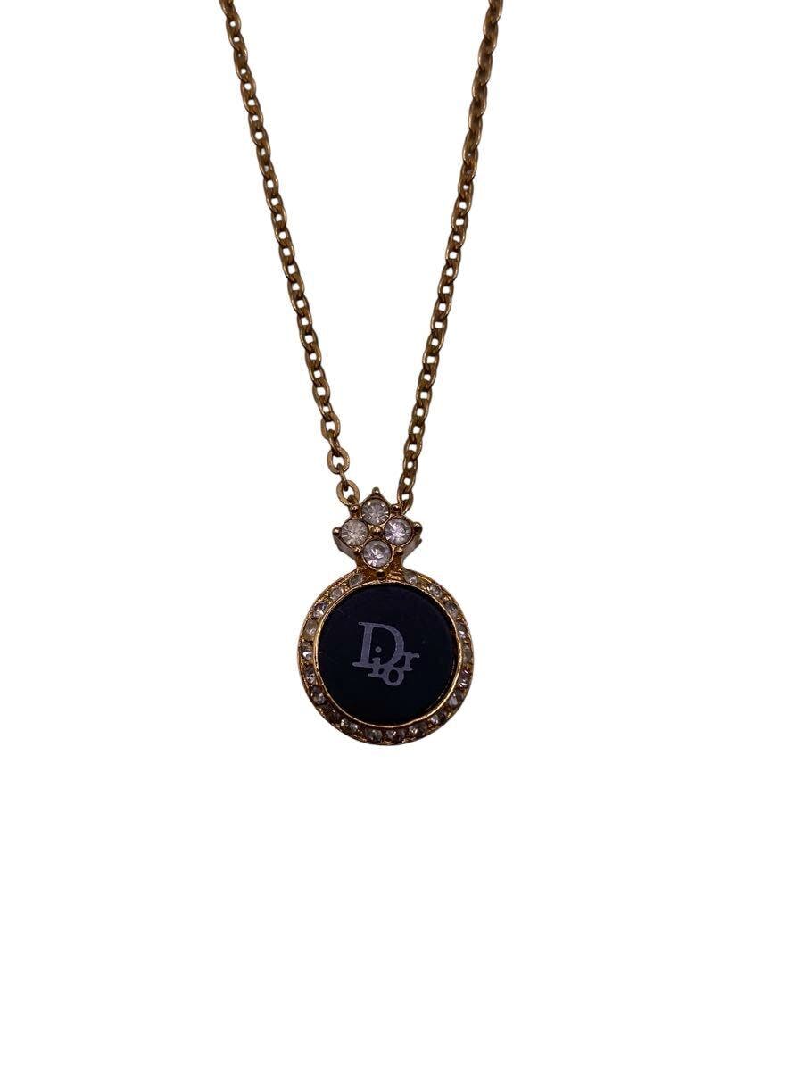 Close-up of a Christian Dior gold-tone necklace pendant with a round black center, surrounding rhinestones, and attached chain.