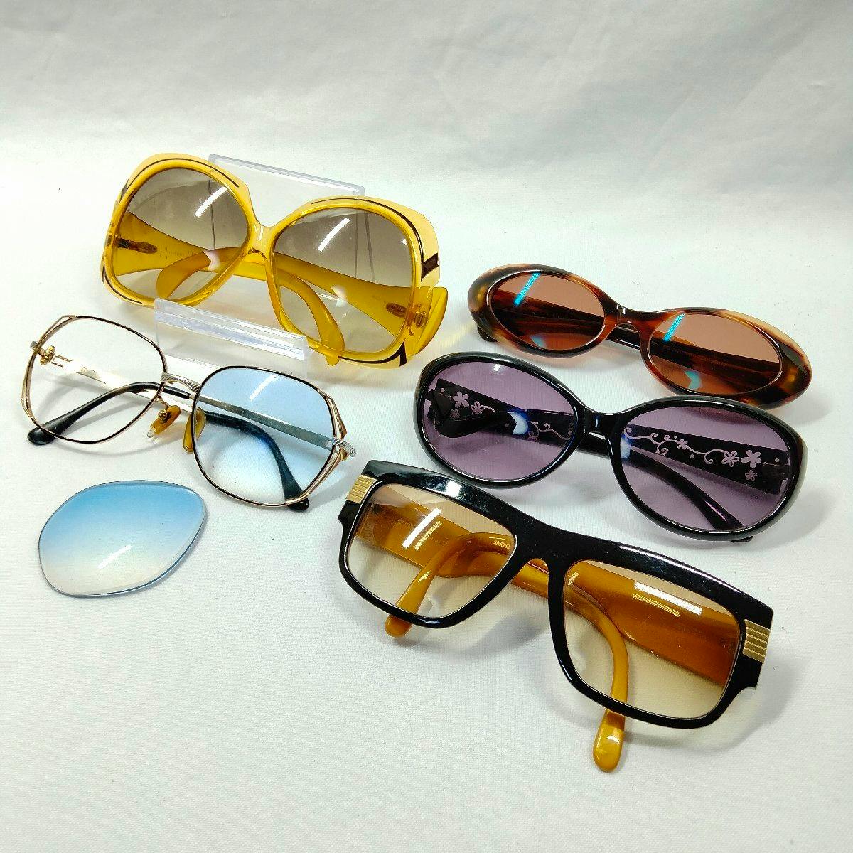 Five plastic sunglasses in different shapes and colors arranged on a white background.