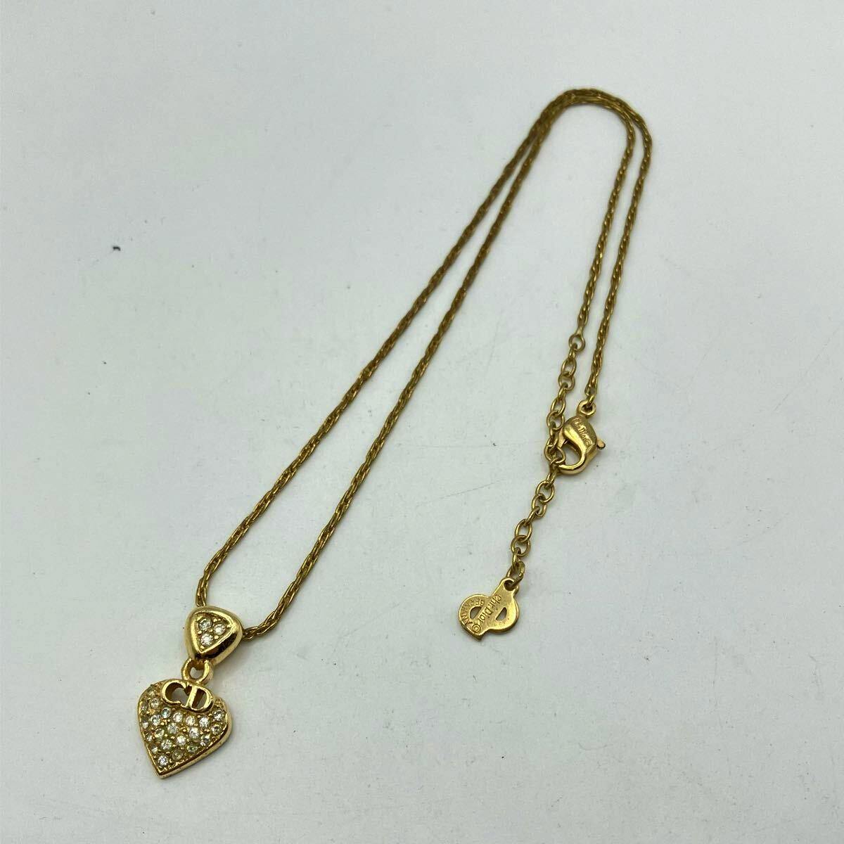 Gold-tone Christian Dior heart pendant necklace with rhinestones and CD logo laid flat showing chain and clasp.