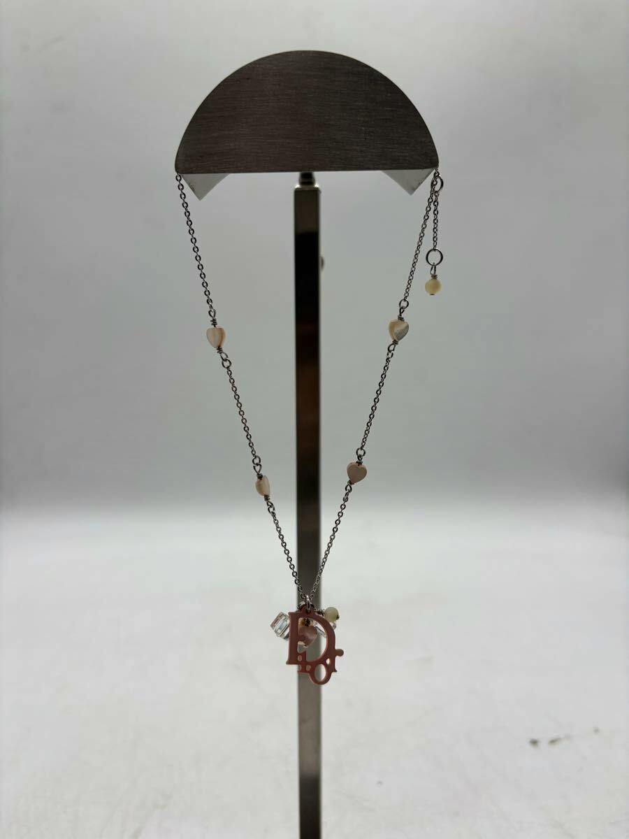 Christian Dior silver-color necklace with small heart motifs and a hanging pendant displayed on a stand.