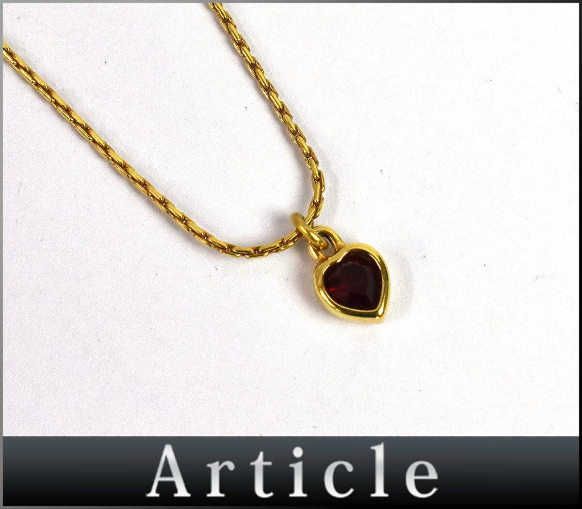 Gold-tone heart pendant necklace with a red heart-shaped stone on a gold chain shown on a white background.