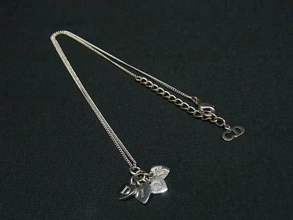 Silver-tone Christian Dior necklace with clustered heart-shaped pendants and chain laid on black fabric.