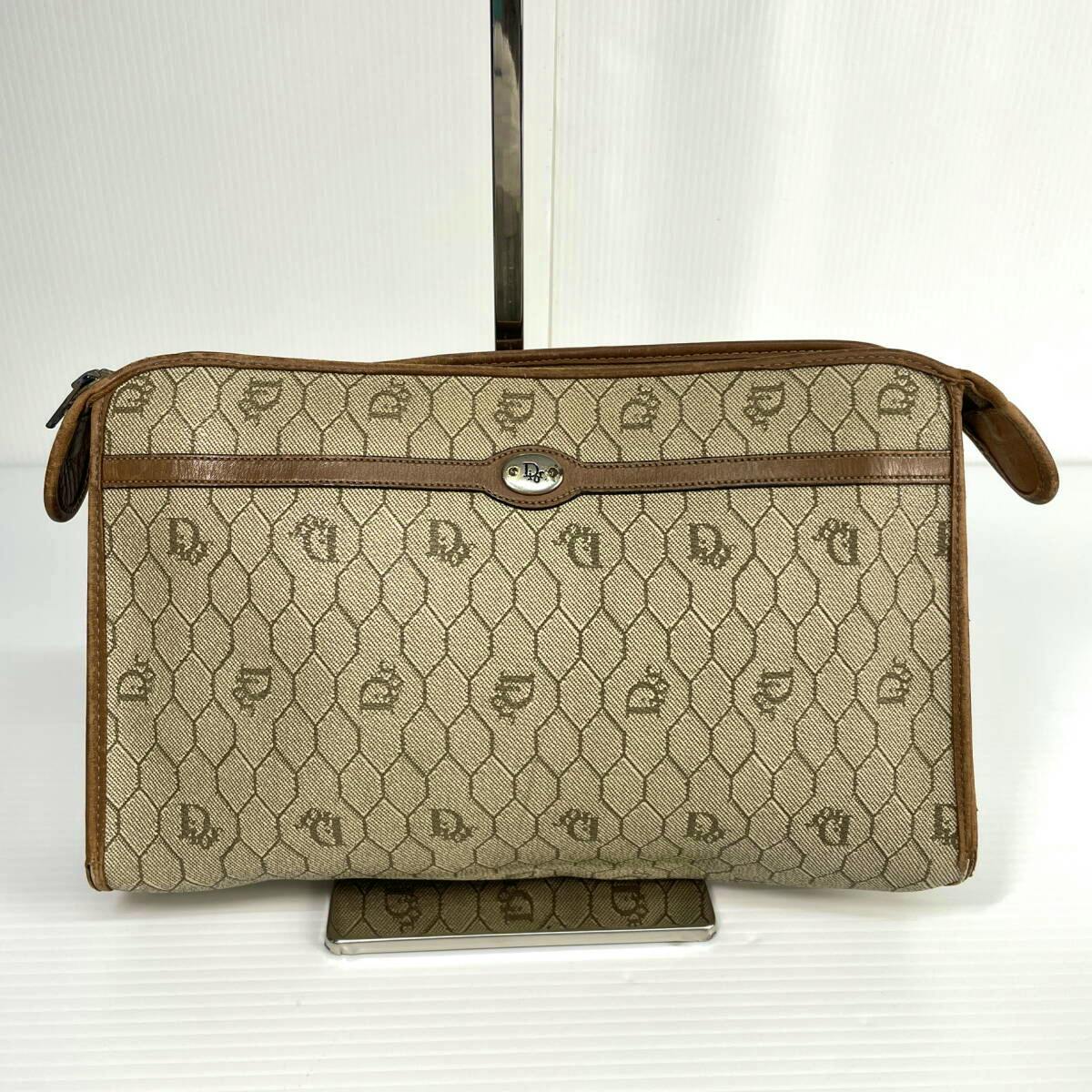 Front exterior of a Christian Dior honeycomb-pattern canvas clutch bag with leather trim and a small metal logo plate.