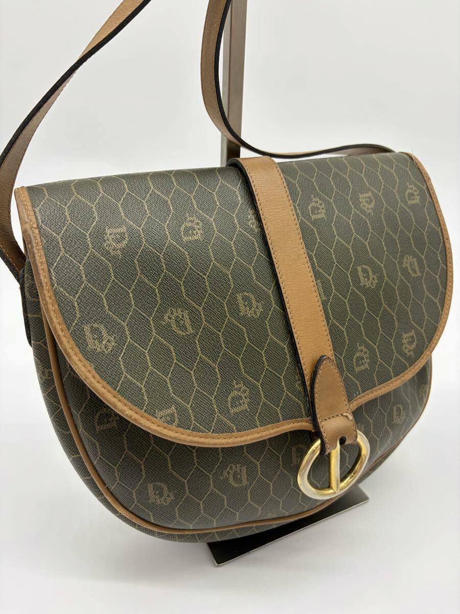 Brown Christian Dior shoulder bag with honeycomb PVC canvas, leather trim, and a front gold-tone buckle.