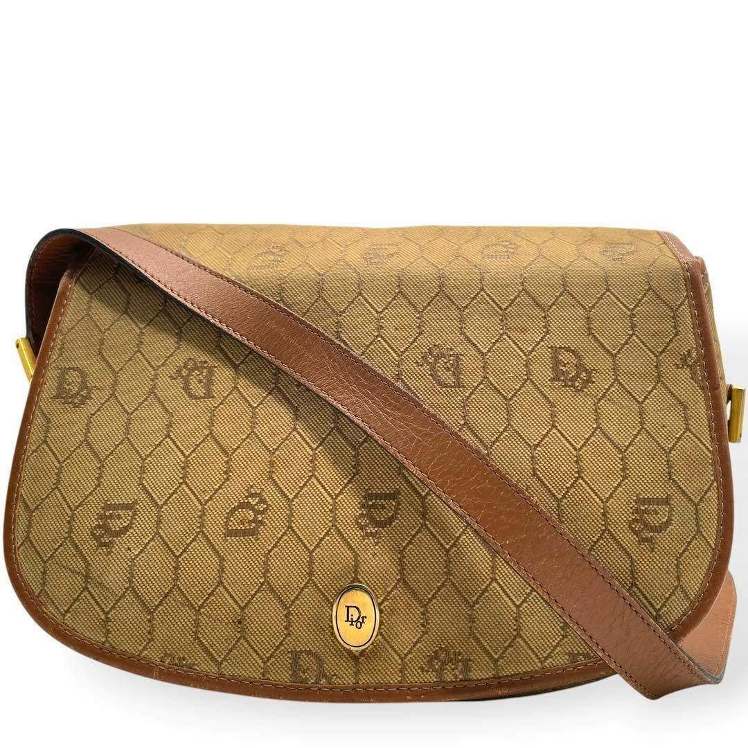 Front view of the Christian Dior canvas shoulder bag showing a honeycomb-patterned exterior, brown leather trim, strap, and an oval Dior emblem.