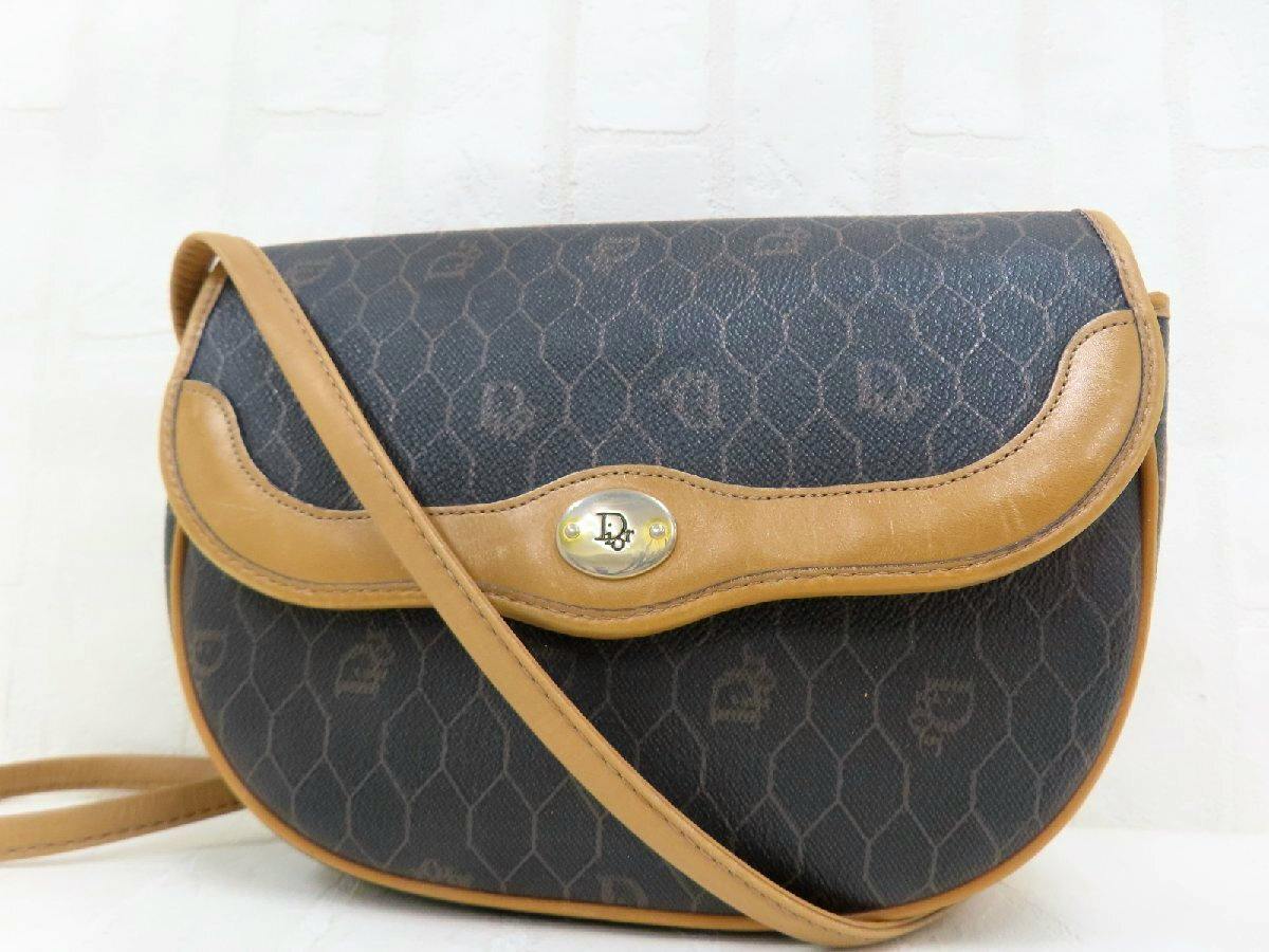 Front view of a Christian Dior shoulder bag in black honeycomb-patterned PVC with brown leather trim, strap, and a gold-tone logo clasp.