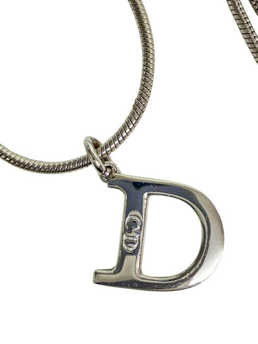 Close-up of a silver-color Christian Dior necklace showing a D initial pendant on a snake-style chain.