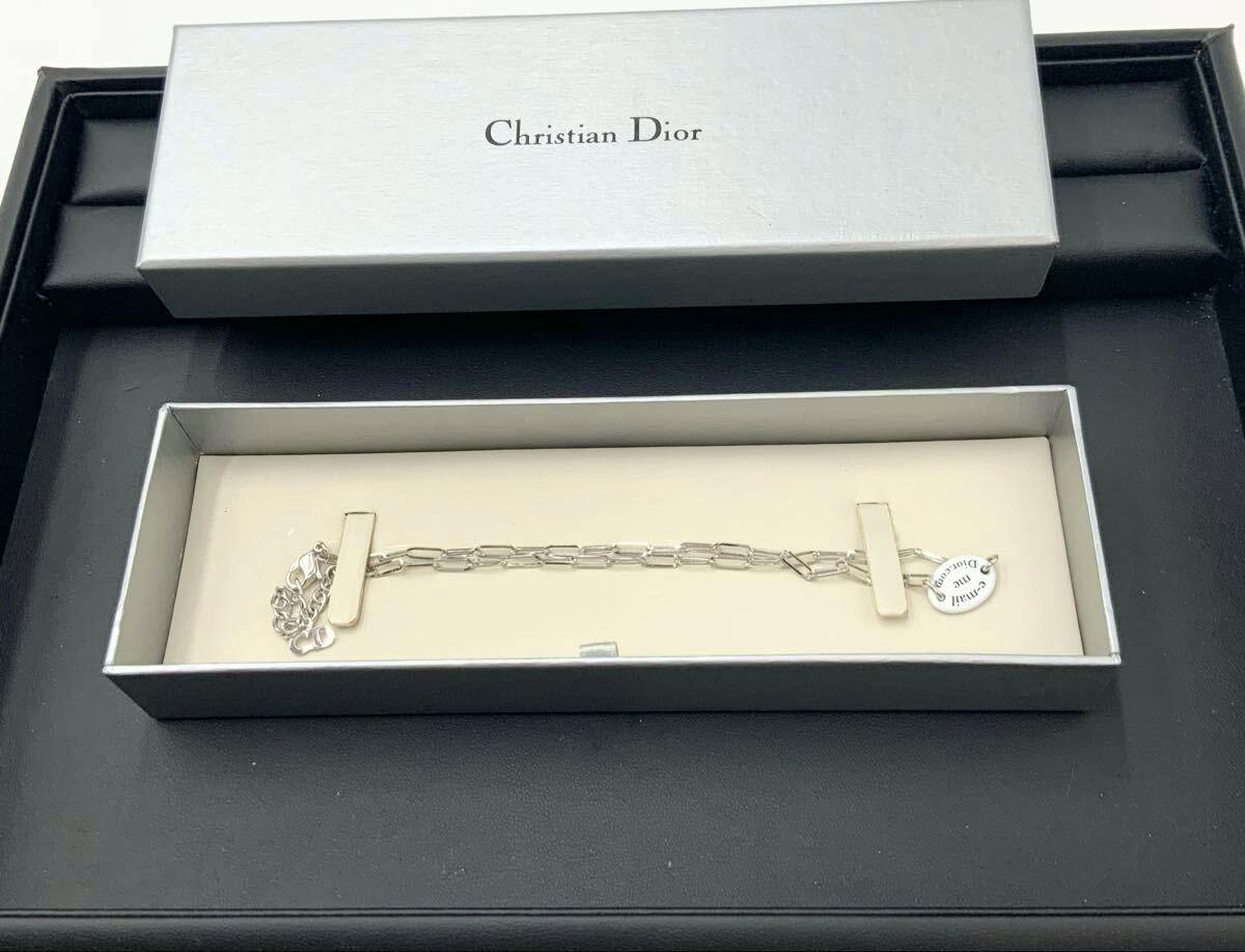 Christian Dior women's necklace with chain and small round Dior tag displayed inside its original box.