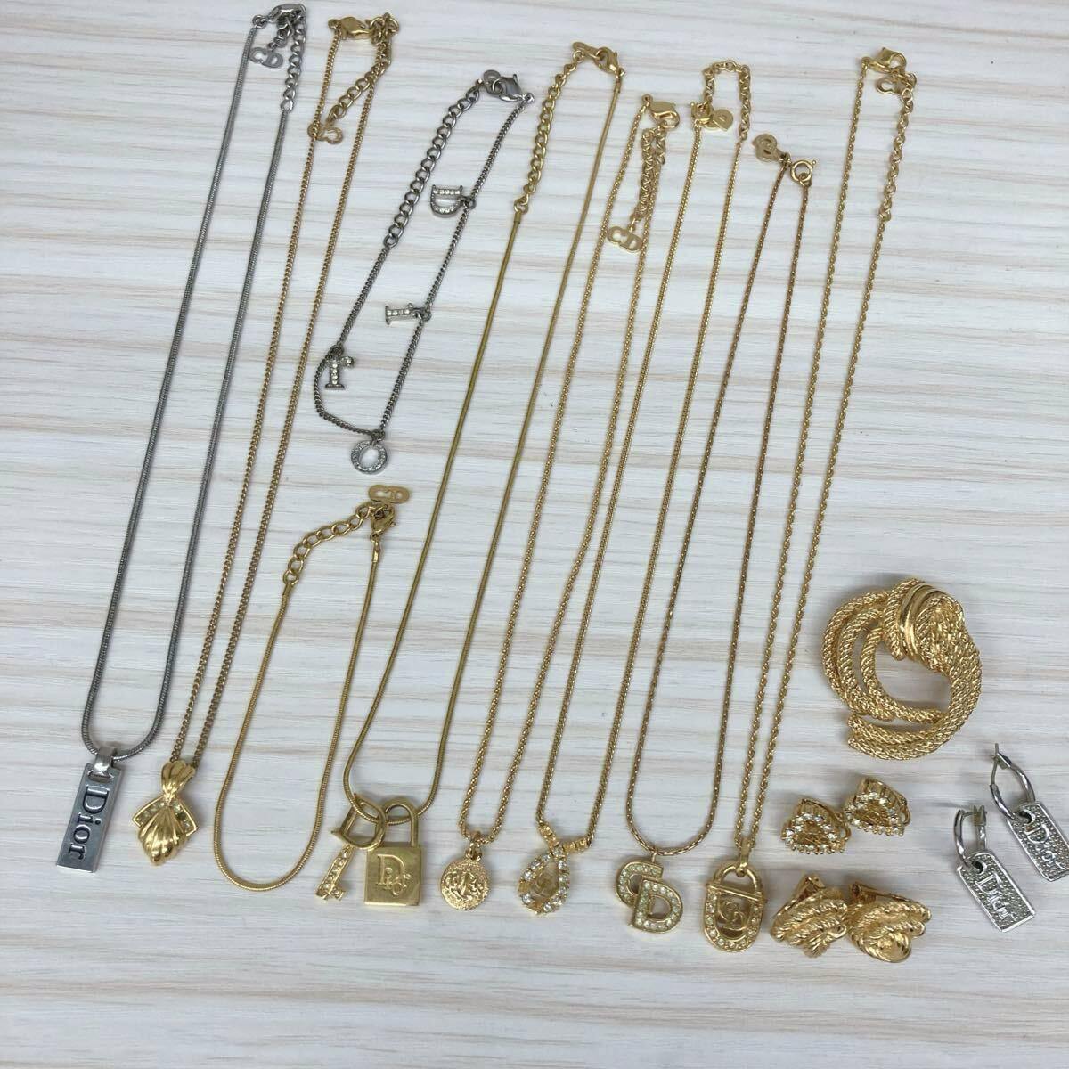 Multiple gold- and silver-tone Christian Dior necklaces, pendants, earrings, bracelets, and brooches arranged on a light wood surface.