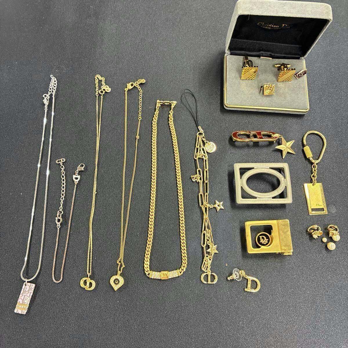 Several Christian Dior gold and silver necklaces, bracelets, brooches, earrings and small accessories laid out on a dark surface.