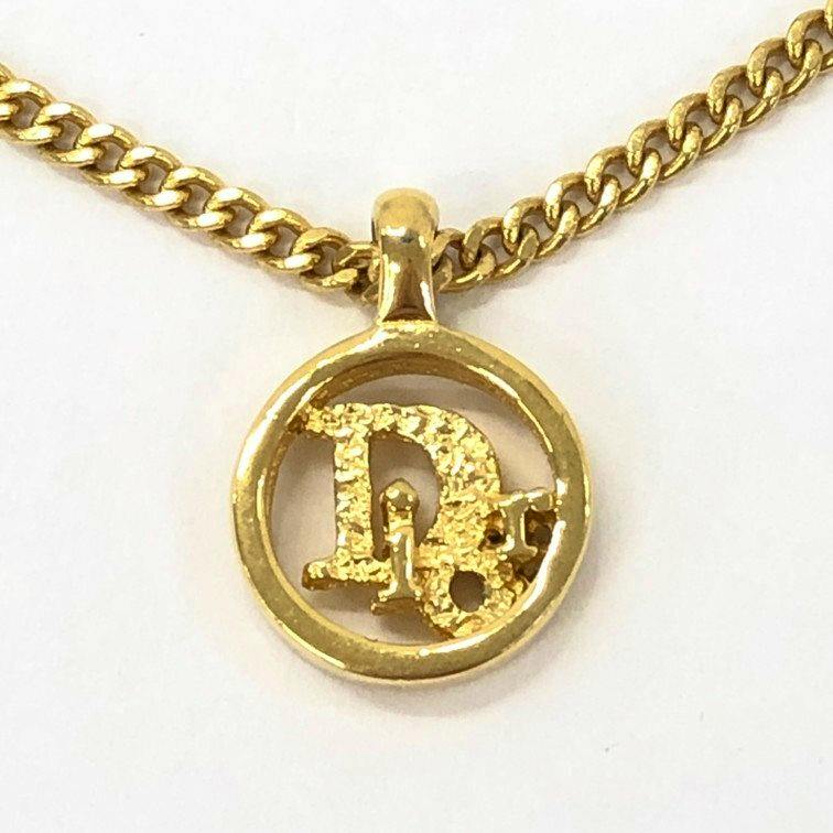Close-up of a gold-tone Christian Dior circular logo necklace pendant on its chain.