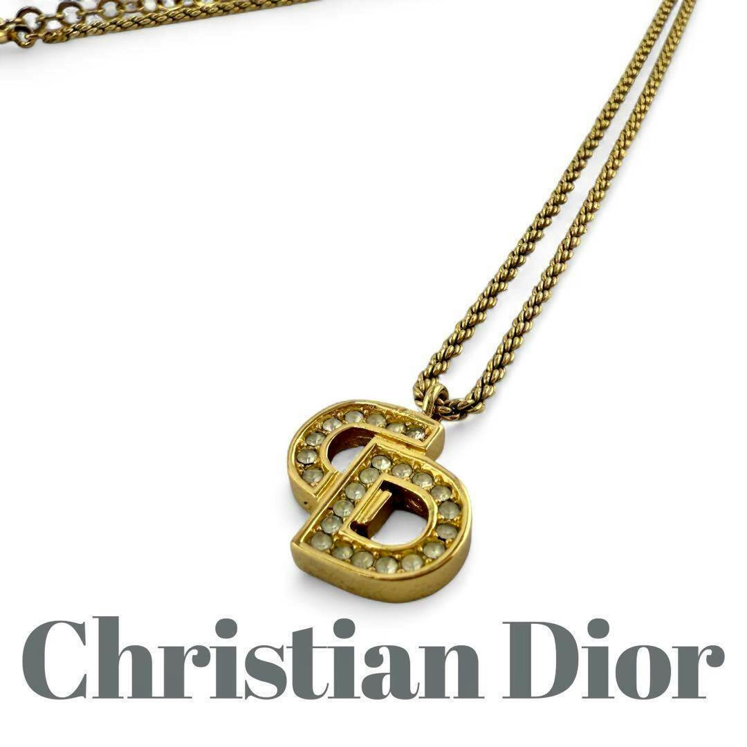 Gold-tone Christian Dior logo pendant necklace with crystal accents and matching chain on a white background.