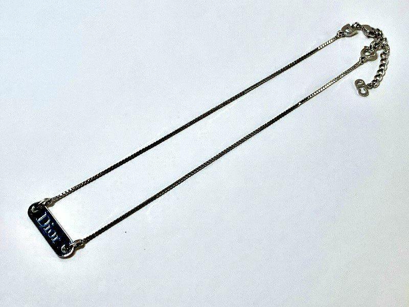 Silver-colored Christian Dior logo plate necklace laid flat on a white background.