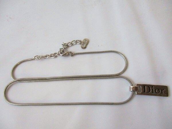 Metal necklace with a rectangular 'Dior' logo plate laid flat on a white background.
