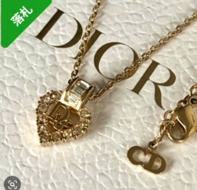 Gold-color Dior necklace featuring a heart-shaped rhinestone pendant and chain with clasp displayed on a Dior-branded background.