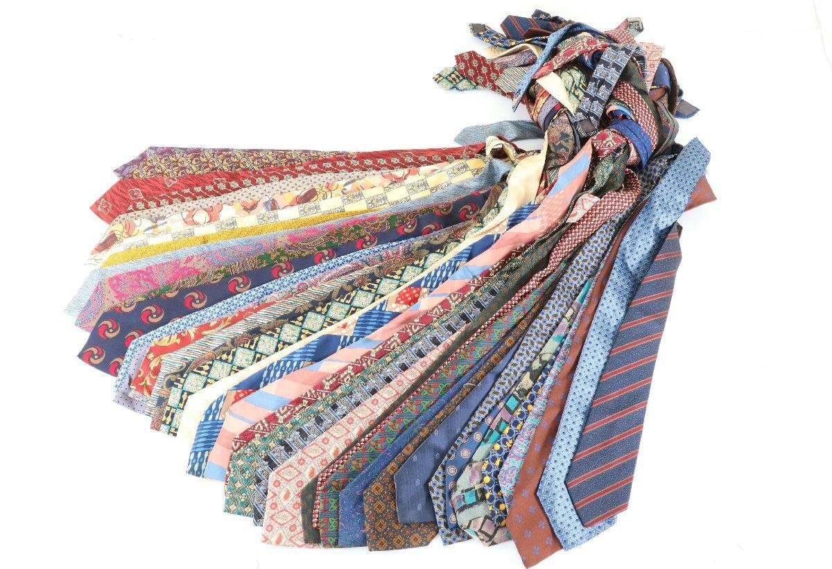 A fan of multiple Christian Dior men's silk neckties in assorted colors and patterns displayed on a white background.