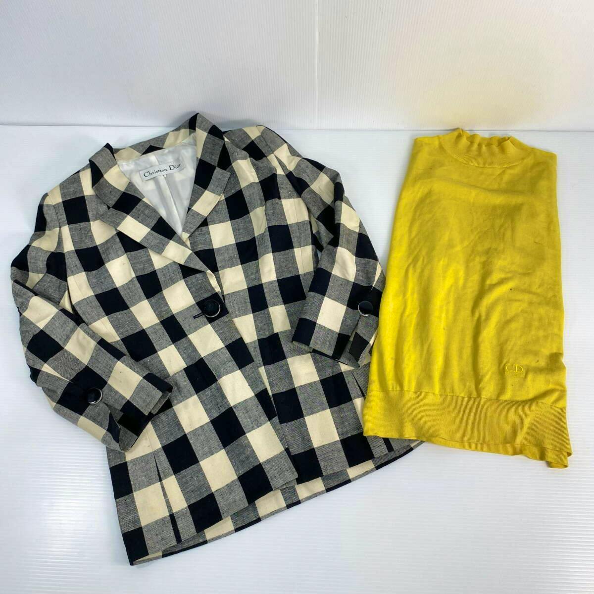 Lay-flat photograph of a black-and-white checked Christian Dior jacket next to a folded yellow knit sweater.