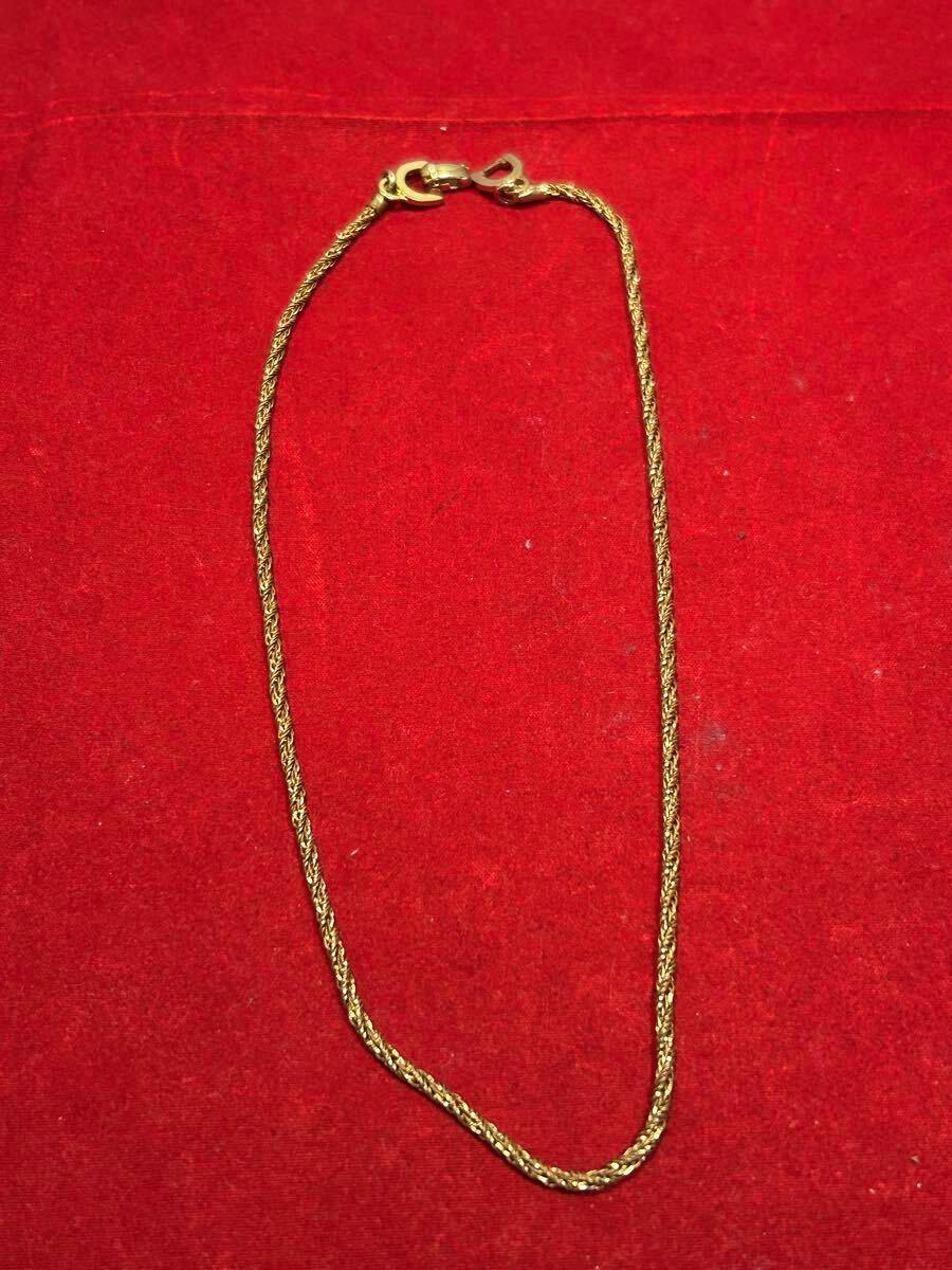 Non-precious metal necklace laid flat on a red background showing the chain and clasp.