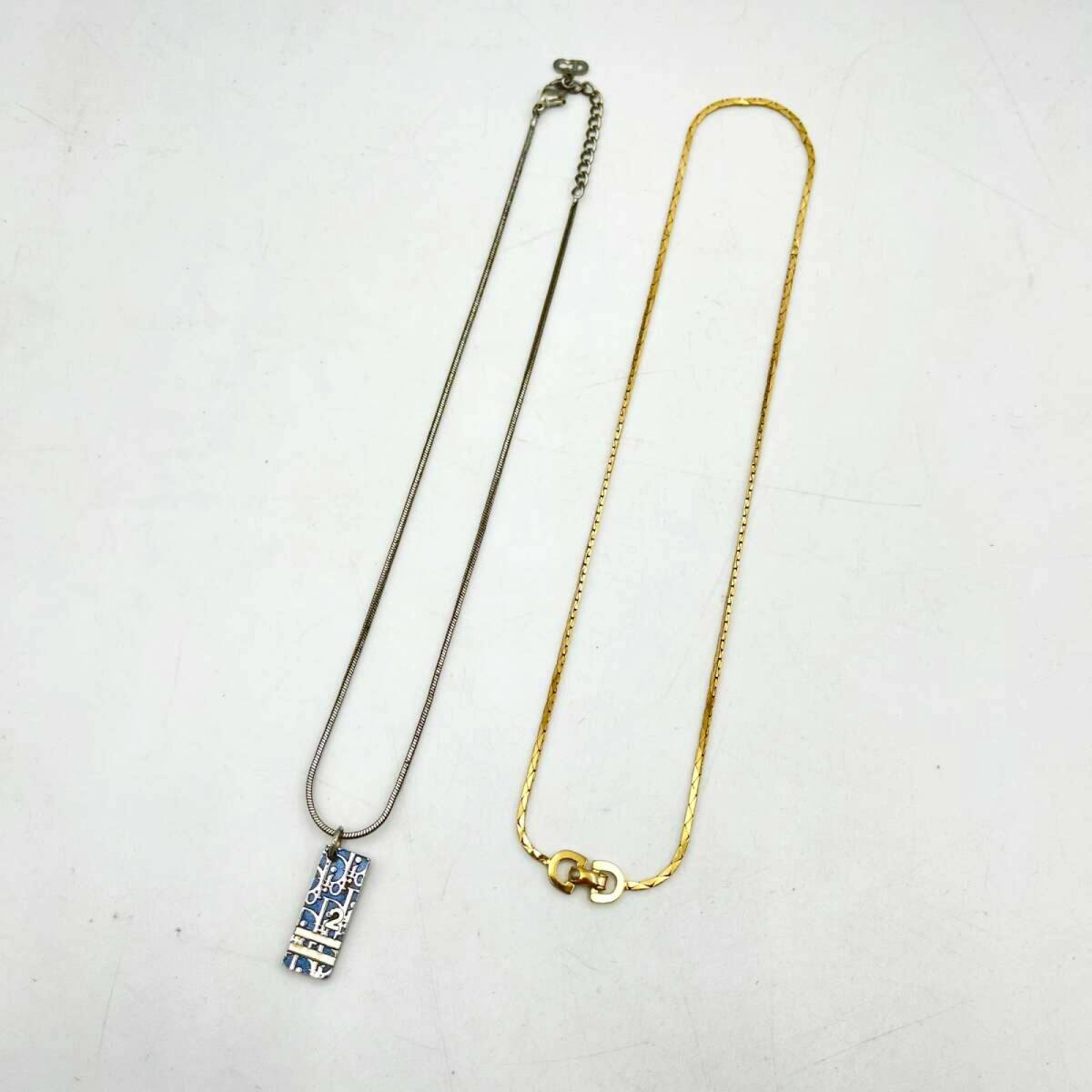 Two necklaces on a white background: a silver chain with a rectangular patterned pendant and a gold chain with an interlocking clasp.