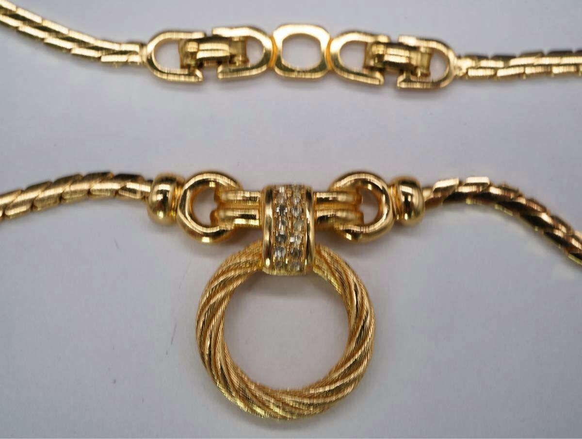 Close-up of a gold-tone Christian Dior necklace showing a twisted circular pendant and chain links.