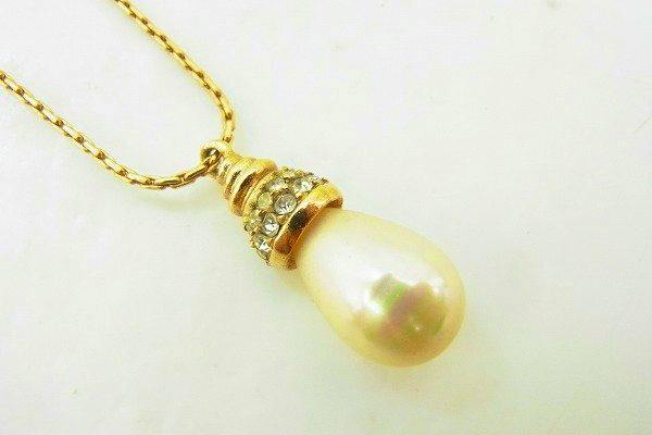 Christian Dior necklace showing a gold-tone chain with a teardrop pearl pendant topped by a rhinestone-set cap.