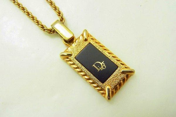 Rectangular Christian Dior pendant with a black center and logo on a twisted rope-style necklace chain.