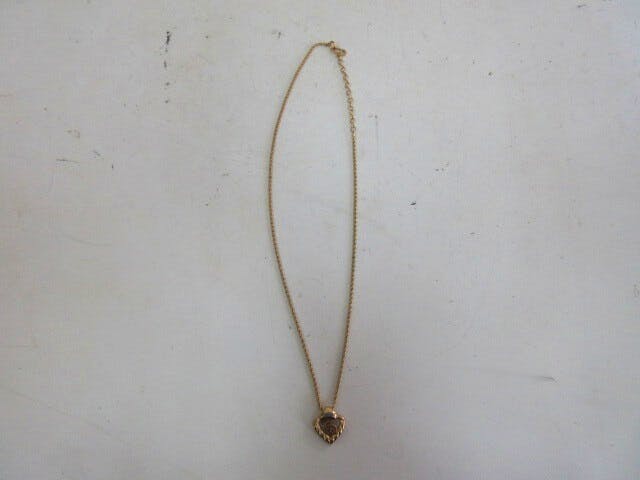 Full-length photo of the Christian Dior non-precious-metal necklace laid flat showing its heart pendant.