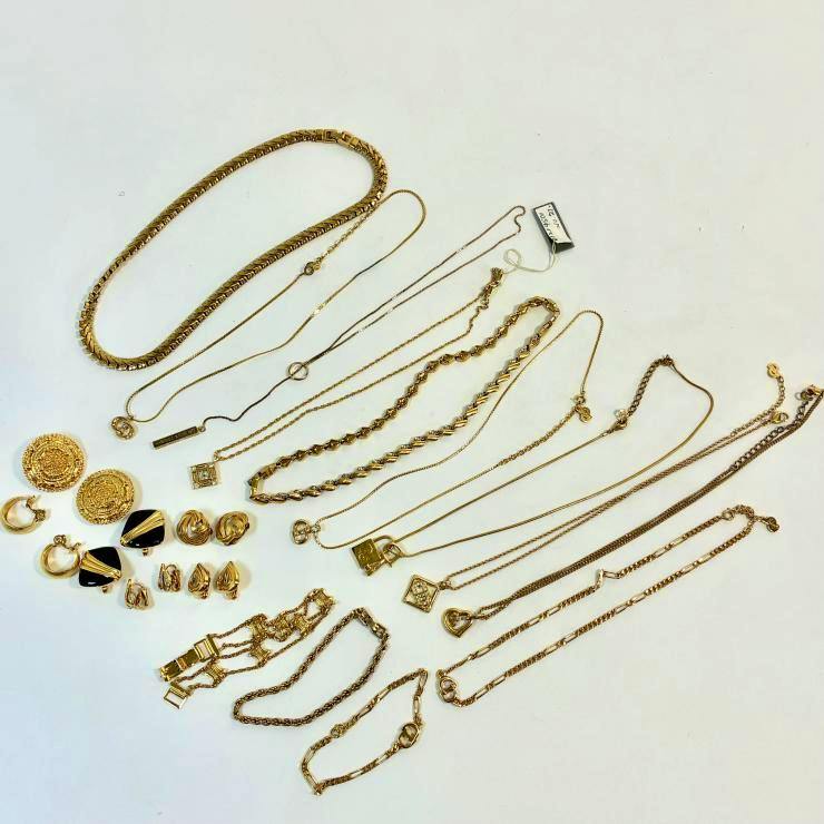 Several gold-colored necklaces, pendants, bracelets and earrings arranged on a white background.