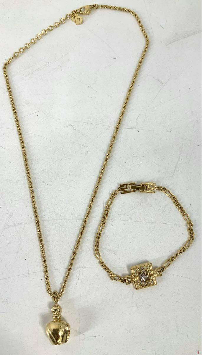 A gold-tone Christian Dior bottle-motif necklace laid flat next to a gold-tone bracelet on a white background.