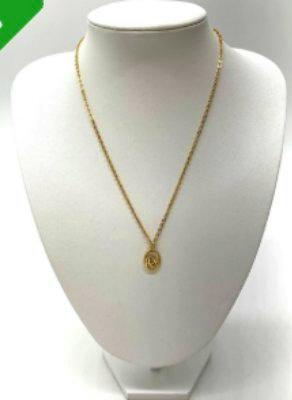 Gold oval-shaped logo necklace on a white display bust.