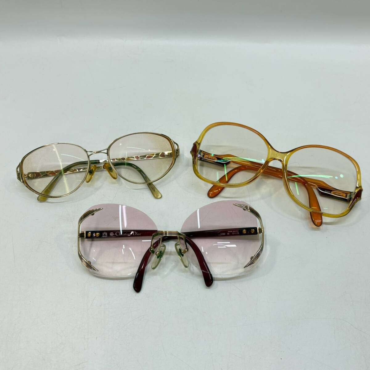 Three pairs of Christian Dior sunglasses/eyeglasses with different colored frames displayed on a white background.