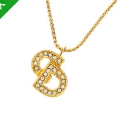 Gold-tone necklace showing a rhinestone-studded CD logo pendant hanging from a twisted chain.